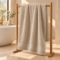 beige Sofia 90x160 cm cotton bath sheet – styled on an oak towel stand in a spa bathroom