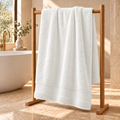white Sofia 90x160 cm cotton bath sheet – styled on an oak towel stand in a spa bathroom